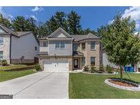 Charming two-story home featuring a manicured lawn, brick accents, a two-car garage, and a neatly landscaped yard at 2004 Brittlebank Ln, Lawrenceville, GA 30043