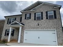 Beautiful two-story home featuring a brick exterior, an attached garage, and a covered entryway at 1636 Jersey Dr, Stockbridge, GA 30281