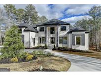 Stunning two-story brick home with a manicured lawn, a circular driveway, and modern gray accents at 4090 Sandy Lake Dr, Lithonia, GA 30038