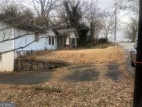 Modest home featuring blue siding, a partially screened porch, and a long driveway leading to the street at 702 Emily Nw Pl # 0, Atlanta, GA 30318