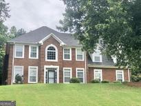 Traditional two-story brick home featuring an arched window and a well-manicured lawn at 1433 Cotton Sw Trl, Conyers, GA 30094