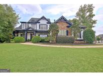 Stunning two-story home with a manicured lawn, stone and siding details, and a welcoming front porch at 383 Beaumont Farms Dr, Sharpsburg, GA 30277