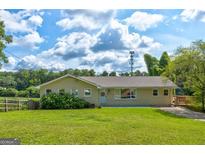 Well-maintained ranch style home featuring a lush lawn, mature trees, and a welcoming front porch at 1848 Winthrop Se Dr, Atlanta, GA 30316