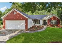 Charming brick and vinyl home with a well-manicured lawn and attached two-car garage at 905 Creekmore Ln, Loganville, GA 30052