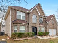 Charming brick two-story home with an attached two-car garage, manicured shrubs, and an arched front entry at 424 Browning Field Way, Hampton, GA 30228