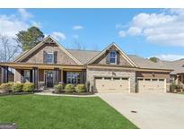 Charming home boasts a three-car garage, stone accents, manicured lawn, and inviting front porch at 266 Hanover Dr, Villa Rica, GA 30180
