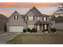 Charming two-story brick home boasts a two-car garage, manicured lawn, and inviting front porch at 3225 Alhambra Cir, Hampton, GA 30228
