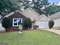 Charming single-Gathering home featuring a brick and stucco exterior with a well-manicured lawn and a two-car garage at 581 N Fairfield Dr, Peachtree City, GA 30269