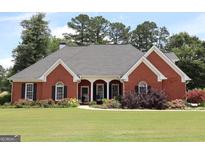 Charming red brick home with a well-manicured lawn and mature landscaping at 405 Mallory Cir, Loganville, GA 30052