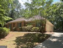 Brick ranch-style home featuring mature trees, a well-maintained lawn, and an inviting, extended driveway at 56 Ridgewood Ct, Mcdonough, GA 30252
