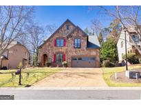 Beautiful stone home featuring a well-manicured lawn and a two-car garage at 4595 Carriage Walk Ln, Cumming, GA 30040