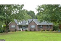 Charming one-story brick home featuring a well-manicured lawn and complemented by lush, mature trees at 219 Brown Branch Rd, Locust Grove, GA 30248