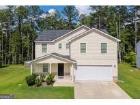 Charming two-story home featuring a covered porch, two-car garage, and well-maintained lawn at 411 Hopi Ln, Villa Rica, GA 30180