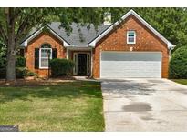 Charming one-story brick home featuring a well-manicured lawn, two-car garage, and inviting front entrance at 2504 Plymouth Way, Conyers, GA 30013