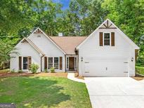 Charming one-story home featuring white siding, brown accents, a manicured lawn and attached two-car garage at 4210 Platinum Ct, Hoschton, GA 30548
