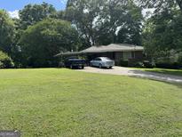 Charming brick home featuring a carport and a well-manicured front yard with mature trees at 537 Elizabeth Sw Ln, Mableton, GA 30126