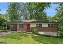 Charming single-story brick home with a red front door, covered parking, and a well-maintained lawn at 4653 Ridgewood Dr, Forest Park, GA 30297
