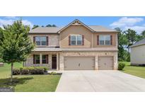 Beautiful two-story home with a manicured lawn, a brick and siding facade, and a three-car garage at 8041 Louis Dr, Locust Grove, GA 30248