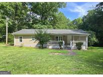 Charming single-story home featuring a welcoming front porch and a well-maintained green lawn at 465 Haynie Rd, Moreland, GA 30259