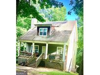 Charming home featuring a covered front porch, wood and vinyl siding, and mature trees in a serene, wooded setting at 2882 Peek Nw Rd, Atlanta, GA 30318
