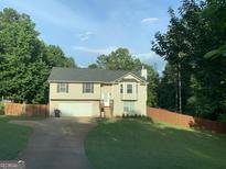 Charming split-level home with a well-maintained lawn and a two-car garage, surrounded by mature trees at 135 Green Commons Dr, Covington, GA 30016
