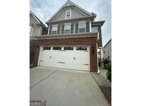 Charming brick home featuring a two-car garage with stylish carriage door and well-manicured lawn at 2060 Lanier Harbor Pt, Buford, GA 30518