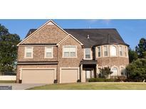 A charming two-story brick home featuring a two-car garage and manicured lawn at 293 Ironwood Dr, Stockbridge, GA 30281