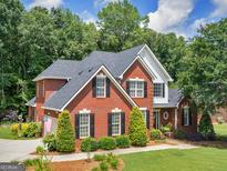 Charming two-story brick home with black shutters, lush green lawn, and mature trees, creating a welcoming curb appeal at 4147 Alayna Lee Cir, Mcdonough, GA 30252