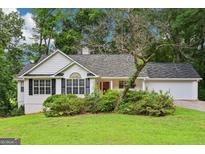 Charming single-story home with white siding, black shutters, and lush landscaping at 345 Sharon Dr, Fayetteville, GA 30214