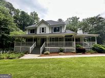 Charming two-story home featuring a wraparound porch and beautiful landscaping at 3970 Governors Cir, Loganville, GA 30052