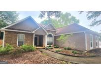 Charming single Gathering home with stone accents, neutral stucco exterior, mature landscaping, and a covered front porch entry at 455 Old Ivy Path, Mcdonough, GA 30253