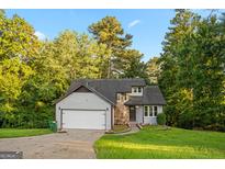 Charming home featuring stone accents, gray siding, and mature trees surrounding the property at 5368 Nw Stafford Nw Dr, Lilburn, GA 30047