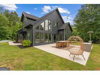 Modern black home with large windows and patio seating area and well manicured lawn at 500 Happy Hollow Rd, Villa Rica, GA 30180