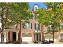 Charming brick townhouse with a one-car garage, black shutters, and mature trees at 56 American Walk, Peachtree City, GA 30269