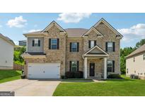 Two-story brick home featuring a manicured lawn, two-car garage, and a welcoming front porch with black shutters at 3711 Wartrace Dr, South Fulton, GA 30331