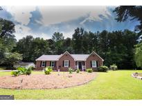 Charming brick home with a well-manicured lawn and complementary landscaping at 155 Granby Ln, Fayetteville, GA 30215