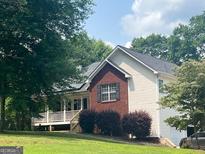 Charming home with brick accents, white siding and a large porch, surrounded by mature trees at 634 Skyline Dr, Villa Rica, GA 30180