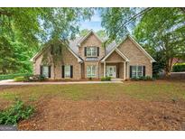 Charming brick home featuring manicured landscaping, black shutters and inviting front porch at 595 Mcgarity Dr, Mcdonough, GA 30252