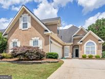 Two-story stucco home with arched entryway, attached garage, and a well-maintained landscaped front yard at 141 Wexford Ct, Stockbridge, GA 30281