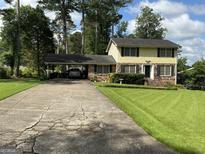 Traditional two-story home with yellow siding, black shutters, a carport, and a well-maintained front lawn at 529 Valley Woods Se Cir, Conyers, GA 30094