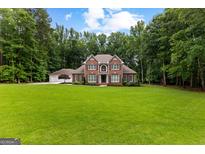 Stately brick two-story home boasts mature trees, a manicured lawn, and a three-car garage at 307 Bellingrath Ct, Peachtree City, GA 30269