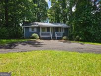 Charming one-story home with a metal roof, inviting porch, and a spacious driveway, surrounded by lush greenery at 602 Mccurdy Rd, Villa Rica, GA 30180