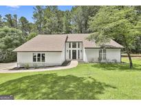 Inviting white home with a well-manicured lawn, complemented by mature trees and tasteful landscaping at 205 Shadowood Ln, Peachtree City, GA 30269