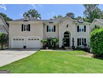 Elegant home featuring a manicured lawn, a large arched front door, and a three car garage at 5245 Cottage Farm Rd, Johns Creek, GA 30022