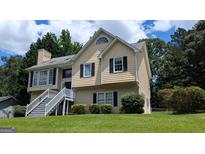 Charming two-story home with a well-maintained lawn, welcoming staircase, and black shutters at 9230 Melody Sw Cir, Covington, GA 30014