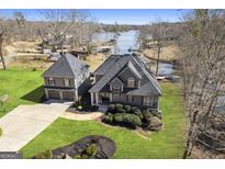 Aerial view of a gray house featuring a well-manicured lawn and lake access on a sunny day at 50 Birch Rd, Covington, GA 30014