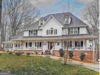 Charming two-story home with a large, welcoming wrap-around porch and mature trees at 125 Sir Lancelot Ct, Fayetteville, GA 30214