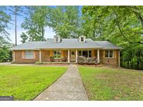 Charming brick home featuring a quaint front porch, two dormers, and a well-manicured front lawn at 1290 Shadowlawn Ne Dr, Conyers, GA 30012