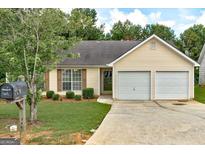 Charming single-story home with a two-car garage, well-maintained lawn, and mature landscaping at 2898 Cedar Trace Dr, Ellenwood, GA 30294