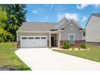 Charming single-Gathering home featuring a two-car garage, red brick accents, and a well-manicured front yard at 7301 Cranleigh St, Covington, GA 30014